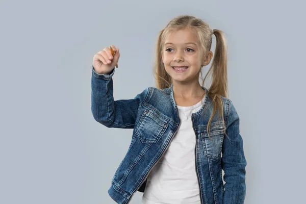 Hermosa niña sostener lápiz escritura feliz sonrisa desgaste pantalones abrigo aislado —  Fotos de Stock