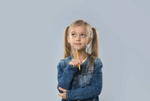 Güzel küçük bir kız izole alan kopyalamak için kalem düşünme ciddi seyir yazma tutun — Stok fotoğraf