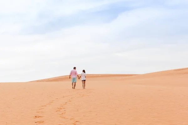 Young Man Woman Walking In Desert Couple Girl And Man Hold Hands Back Rear View Sand Dune Landscape