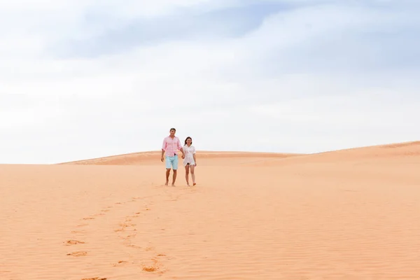 Jeune homme femme marche dans le désert couple fille et homme tenir les mains sable dune paysage — Photo