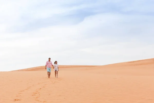 Jeune homme femme marche dans le désert couple fille et homme tenir les mains sable dune paysage — Photo