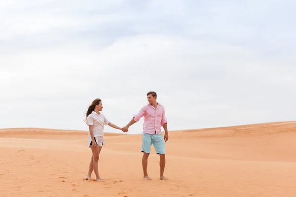 Junger Mann Frau zu Fuß in Wüste Paar Mädchen und Mann halten Hände Sanddünenlandschaft — Stockfoto