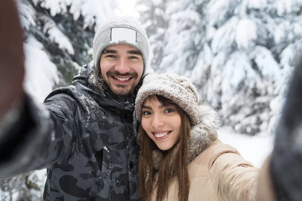 Мужчина делает селфи фото Молодая романтическая пара улыбка снежный лес на открытом воздухе — стоковое фото