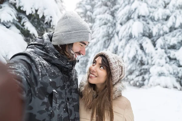 Az ember vesz Selfie fénykép fiatal romantikus pár mosoly hó erdő szabadtéri — Stock Fotó