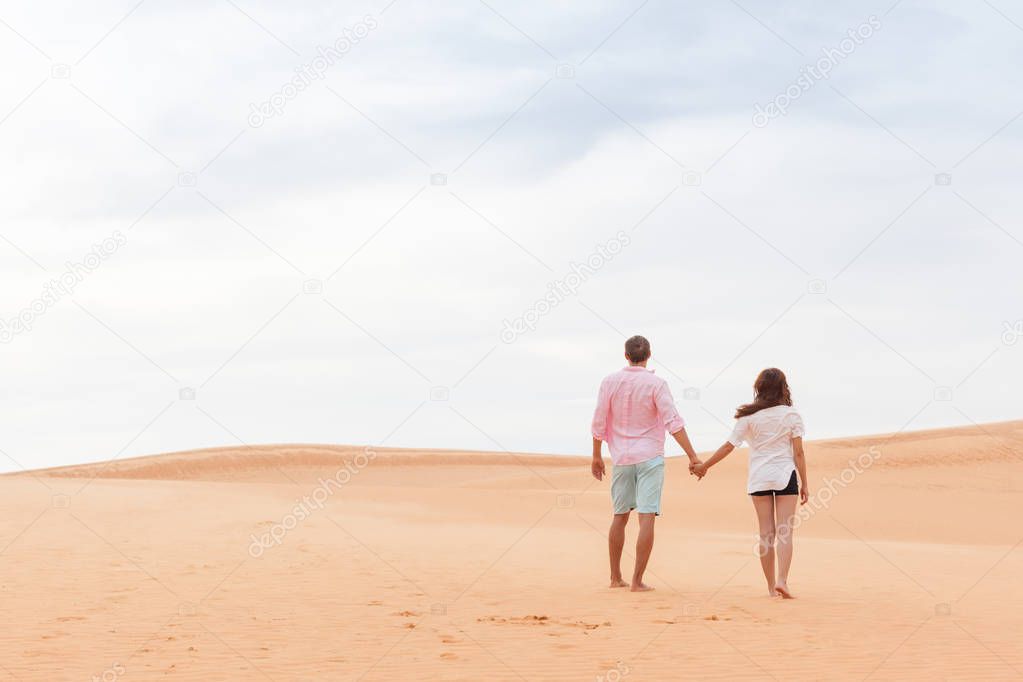 Young Man Woman Walking In Desert Couple Girl And Man Hold Hands Back Rear View Sand Dune Landscape
