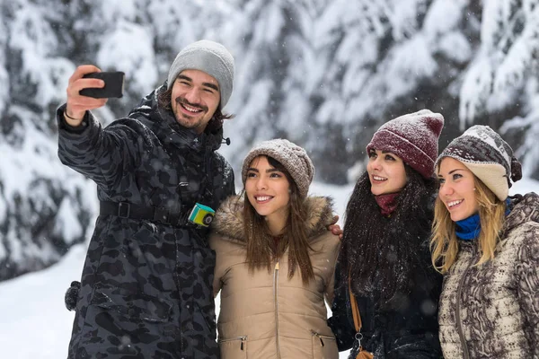 Az ember tartsa intelligens telefon kamera véve Selfie fotó meg mosoly hó erdő fiatal emberek csoport szabadtéri — Stock Fotó