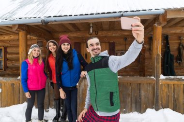 İnsanlar akıllı telefon ahşap Country House kış kar yakınındaki Selfie fotoğrafta grup Cottage Resort