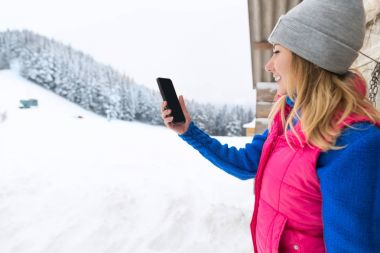 Fotoğraf akıllı telefon karlı dağ genç kadın kış kar alarak kız