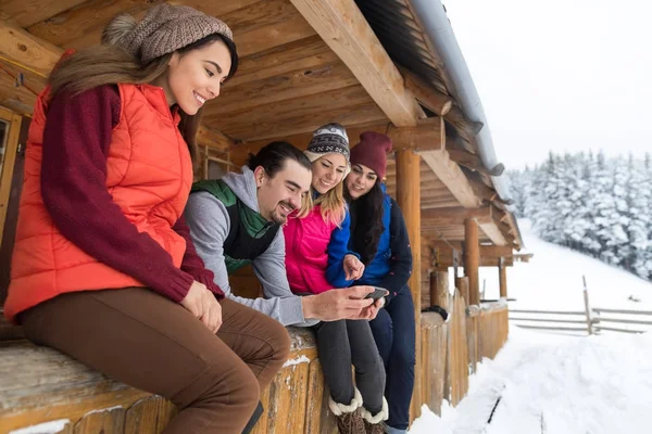 Segítségével intelligens telefon beszélgető szabadtéri üzenetküldő internetes fa Country House télen a hó emberek csoport Resort Cottage — Stock Fotó