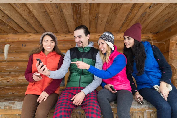 Ομάδα ατόμων χρησιμοποιώντας έξυπνο τηλέφωνο μηνυμάτων Internet ξύλινα χώρα σπίτι χειμώνα χιόνι στο βουνό θέρετρο εξοχικό σπίτι — Φωτογραφία Αρχείου