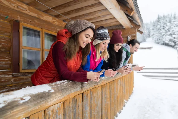 People Group using Smart Phone Messaging Internet Wooden Country House Winter Snow Mountain Resort Cottage — стоковое фото