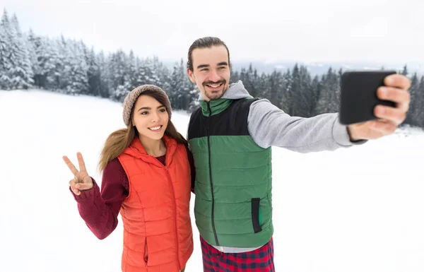 Akıllı telefon karlı Köyü adam kadın kış dağ kar üzerinde Selfie fotoğraf çekici çift — Stok fotoğraf