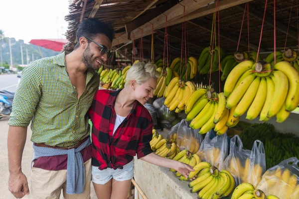 Pareja comprando plátanos en el mercado tradicional callejero, viajeros de hombres y mujeres jóvenes — Foto de Stock