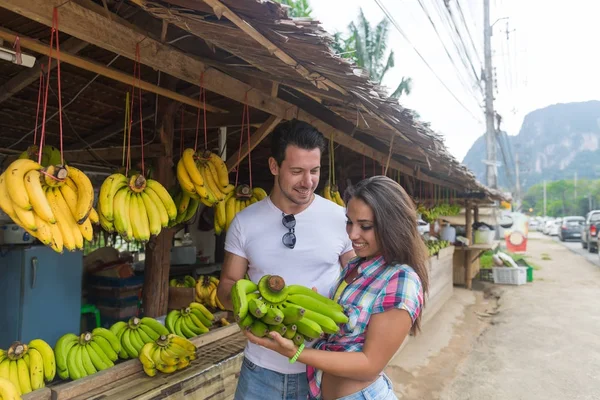 Pareja comprando plátanos en el mercado tradicional callejero, viajeros de hombres y mujeres jóvenes —  Fotos de Stock
