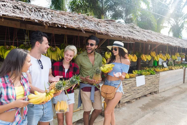 Groupe de personnes achetant des bananes et des ananas sur le marché traditionnel de la rue, jeunes hommes et femmes voyageurs — Photo