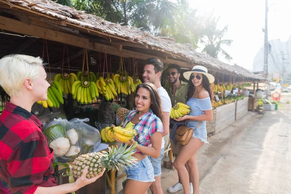 Grupo de personas que compran plátanos y piñas en el mercado tradicional callejero, viajeros de hombres y mujeres jóvenes — Foto de Stock