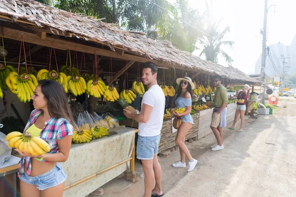 Gruppo di persone l'acquisto di banane e ananas su strada mercato tradizionale, giovane uomo e donna viaggiatori — Foto Stock