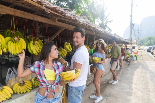 Pareja comprando plátanos en el mercado tradicional callejero, viajeros de hombres y mujeres jóvenes — Foto de Stock