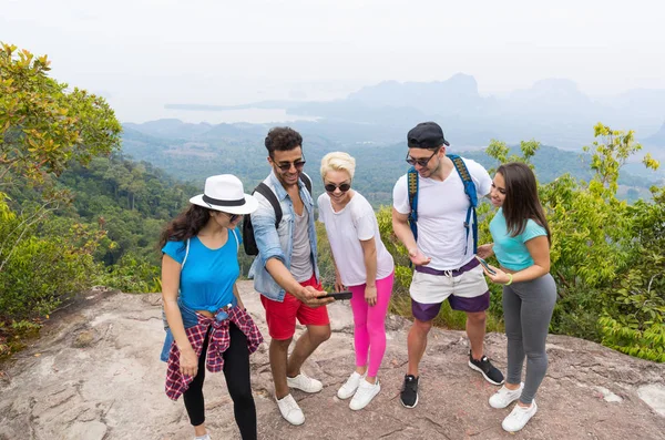Gruppo turistico guarda le foto su telefoni cellulari intelligenti, persone con zaino sul paesaggio dalla cima della montagna — Foto Stock