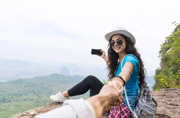 Mujer con mochila tomar una foto del paisaje de la cima de la montaña en el teléfono inteligente celular que sostiene la mano del hombre — Foto de Stock