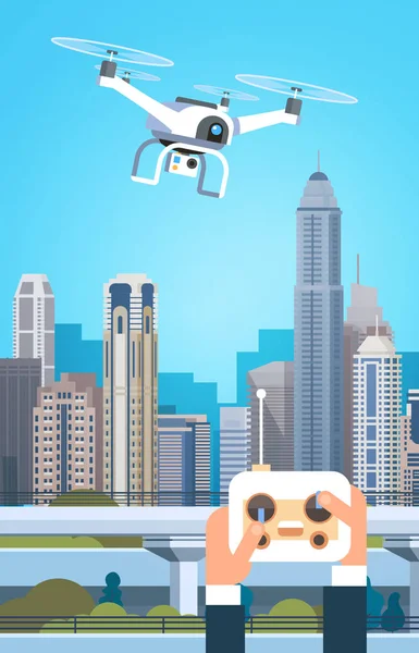 As mãos que prendem o controlador remoto para o drone moderno voam sobre edifícios da cidade —  Vetores de Stock