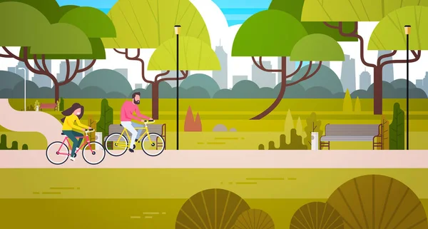 Pareja montando bicicletas en parque público sobre ciudad edificio horizonte fondo hombre y mujer ciclismo al aire libre — Vector de stock