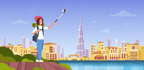 Turista mujer con mochila tomando foto selfie sobre hermoso fondo de la ciudad de Dubai — Archivo Imágenes Vectoriales