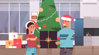 Mutlu noeller Noel kutlaması konsepti. Noel baba şapkalı kadın. Formda ağaç ve modern oturma odasının yanında duruyor.