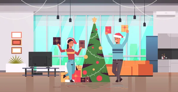 Пара тримає загорнуті подарункові коробки веселі різдвяні щасливі новорічні свята концепція святкування чоловік жінка в капелюхах Санта сучасна вітальня інтер'єр квартира повної довжини горизонтальна — стоковий вектор