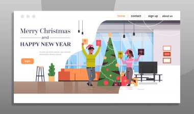 Çiftler hediye kutuları taşıyor mutlu noeller yeni yıl kutlamaları kadın Noel baba şapkalı modern oturma odası iç mekan tam boy fotokopi odası yatay