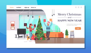 Çiftler hediye kutuları taşıyor mutlu noeller yeni yıl kutlamaları kadın Noel baba şapkalı modern oturma odası iç mekan tam boy fotokopi odası yatay