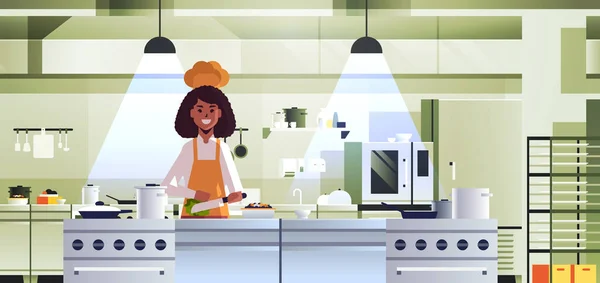 Cocinero profesional hembra cortar verduras en tabla de tallar mujer afroamericana en uniforme preparar ensalada cocina concepto de comida restaurante moderno cocina interior retrato horizontal — Vector de stock