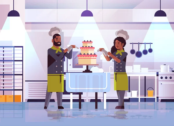 Professionele gebak chef-koks paar versieren smakelijke bruiloft crème cake Afrikaanse Amerikaanse vrouw man in uniform koken Food concept plat modern restaurant interieur volledige lengte horizontaal — Stockvector