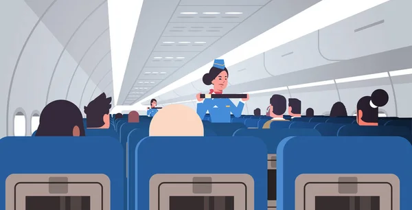 Hôtesse de l'air expliquant aux passagers comment utiliser la fixation de la ceinture de sécurité dans les situations d'urgence agents de bord en uniforme concept de démonstration de la sécurité intérieur de l'avion horizontal — Image vectorielle