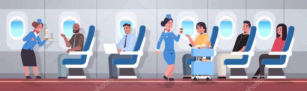 flight attendants serving mix race passengers stewardesses in uniform offering drinks professional service travel concept modern airplane board interior full length horizontal flat