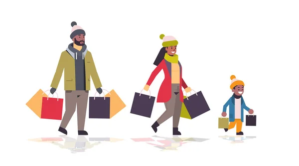 Família andando com sacos de papel coloridos Feliz Natal feliz ano novo inverno conceito de compras pais afro-americanos com criança segurando compras comprimento total horizontal —  Vetores de Stock