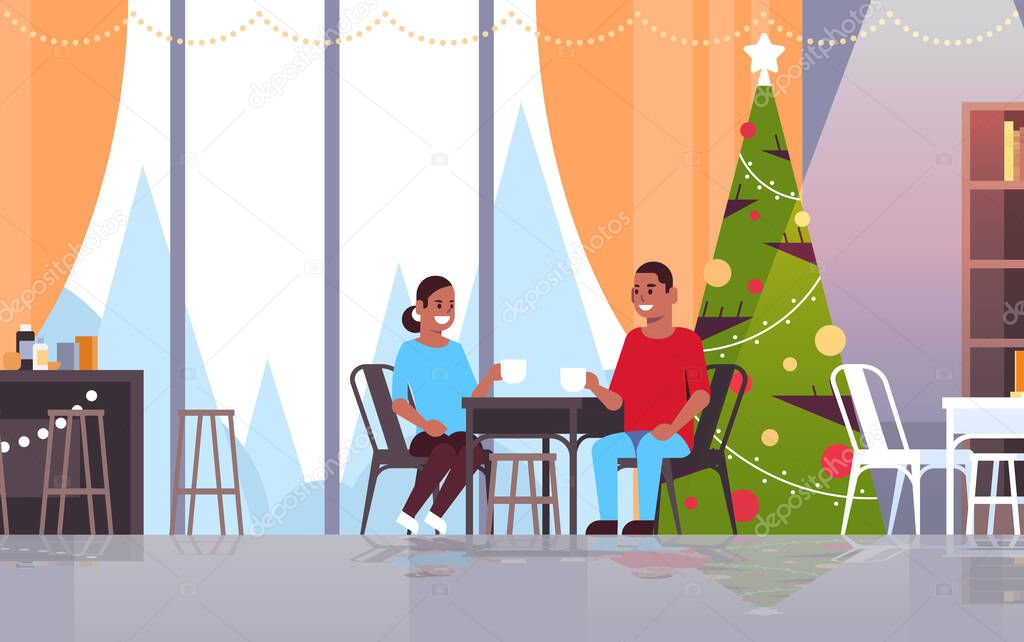 african american couple sitting at cafe table drinking coffee and discussing during meeting merry christmas happy new year holidays concept modern restaurant interior flat full length horizontal