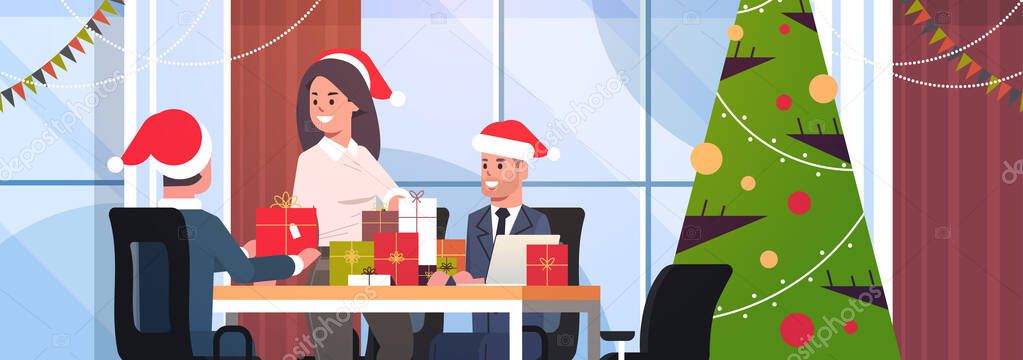 businesswoman congratulating male colleagues with merry christmas happy new year holidays businesspeople at workplace holding gift present boxes modern office interior flat portrait horizontal
