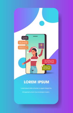 Noel Baba şapkalı kadın sohbet uygulaması sosyal ağ iletişimi kullanıyor Noel bayramı kutlaması konsepti akıllı telefon ekranında hediye kutusu olan online mobil uygulama portresi dikey