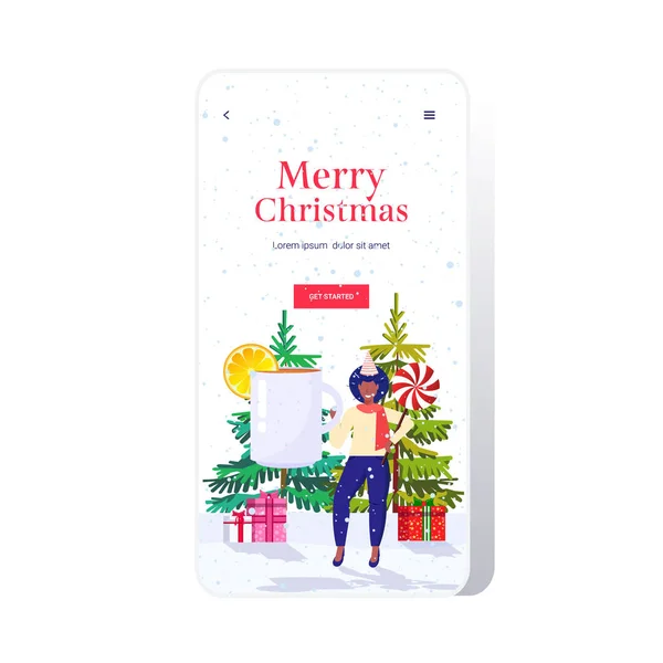 African american girl christmas drink mulled wine and candy lollipop winter holidays celebration concept smartphone screen online mobile app full length greeting card — Stock Vector