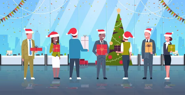Бізнесмени святкують корпоративну вечірку мікс гоночні колеги в капелюхах Санти, що тримають подарункові коробки веселих різдвяних щасливих новорічних свят концепція сучасного офісного інтер'єру повної довжини горизонтальна — стоковий вектор