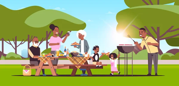 Famiglia multi generazione preparare hot dog sulla griglia pic-nic barbecue partito concetto estate parco paesaggio fondo piatto tutta la lunghezza orizzontale — Vettoriale Stock