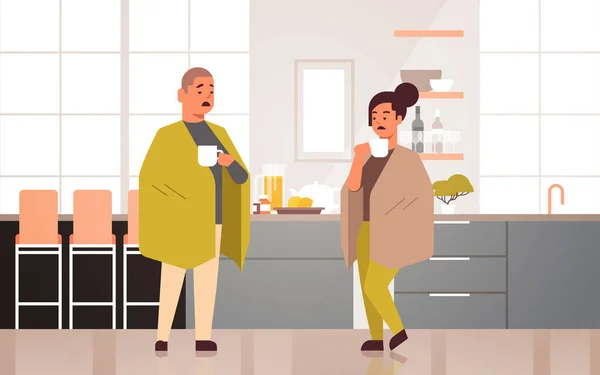 Sick couple drinking hot tea unhealthy man woman covered with blanket suffering from cold flu virus illness concept modern home kitchen interior flat full length horizontal — Stock vektor