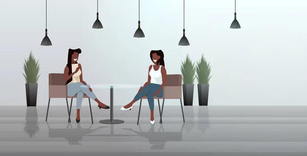 Donne sedute al tavolo del caffè afro-americano ragazze coppia discutendo durante l'incontro ristorante moderno interno schizzo orizzontale lunghezza intera — Vettoriale Stock