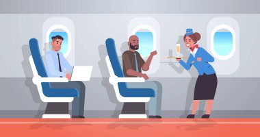 Uçuş görevlisi üniformalı hostese alkollü içecek servisi yapıyor. Elinde şampanya kadehi, profesyonel servis konsepti uçak konsepti. İç kısmı yatay.