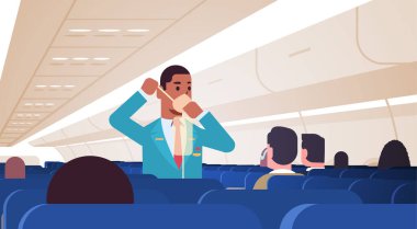 Yolculara acil durumlarda oksijen maskesinin nasıl kullanılacağını açıklayan hostes Afro-Amerikan erkek uçuş görevlisi güvenlik gösterimi konsepti modern uçak panosu iç yatay