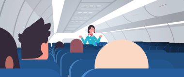 Hostes, acil durum çıkışlarını gösteren üniformalı kadın uçuş görevlileri için talimatları açıkladı.