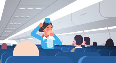 Hostes yolculara acil durum uçuş görevlisi güvenlik tanıtım konseptinde oksijen maskesinin nasıl kullanılacağını anlatıyor.