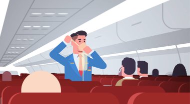 Kamarot yolculara acil durumlarda oksijen maskesinin nasıl kullanılacağını açıklıyor. erkek uçuş görevlisi güvenlik gösterimi konsepti modern uçak tahtasının iç kısmı