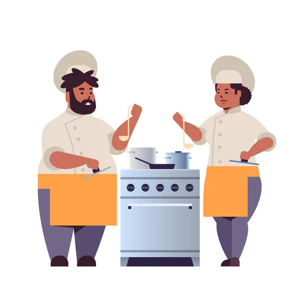 Aşçılar çift profesyonel şefler hazırlama ve yemekleri tatma afrikalı-amerikalı kadın adam restoran işçileri üniforma lı birlikte mutfak sobası pişirme gıda kavramı düz tam uzunlukta yakınında ayakta — Stok Vektör